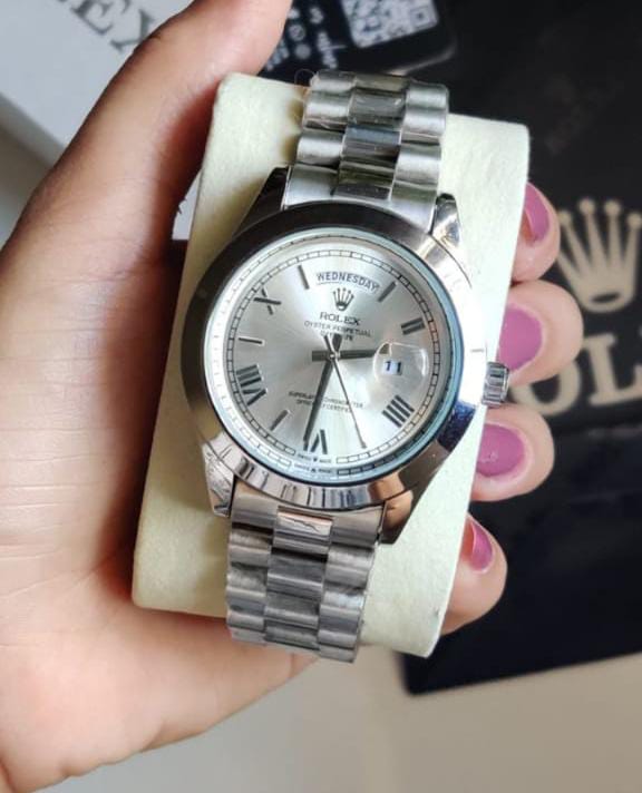 Rolex Day-Date is a luxury timepiece featuring a silver dial with Roman numerals and a matching silver stainless steel bracelet.